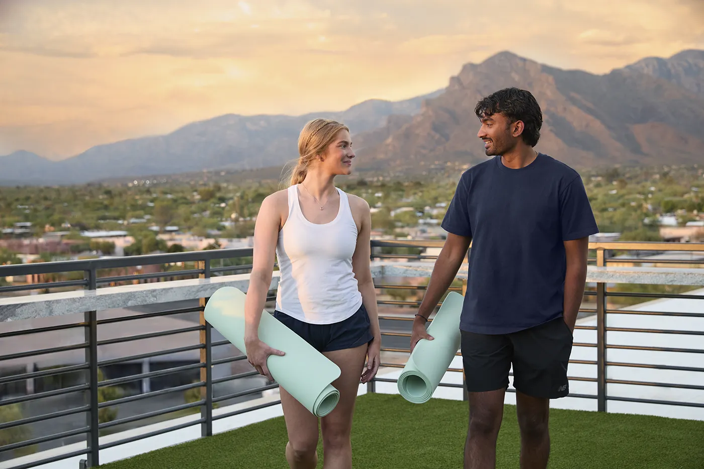 The Astrie residents carrying yoga mats on a rooftop terrace with Tucson mountain views